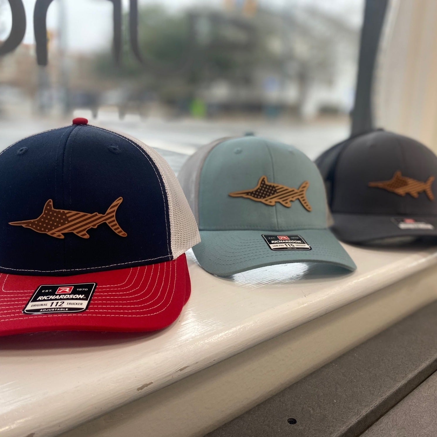 Three different styles of Marlin hat sitting in a window. 