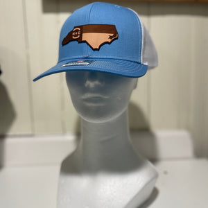 Blue and white hat with a North Carolina shape emblem with the NC flag on it