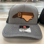 Load image into Gallery viewer, Grey and black hat with a North Carolina shape emblem with the NC flag on it

