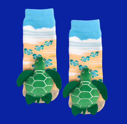 Baby turtle socks with a beach background and turtle plush on the toes. 