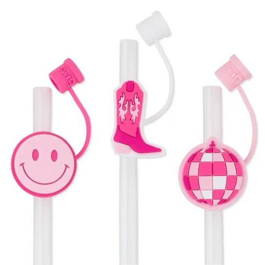 Three pink straw toppers on clear straws. Left is a smiley face, middle a cowgirl boot, right disco ball. 